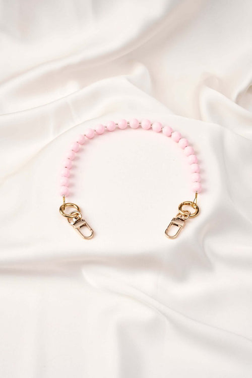 strap celular artesanal Blush Moment en color rosa con broches de oro, elaborado a mano por artesanas colombianas.