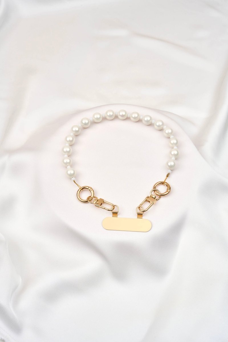 strap corto para celular artesanal con perlas y broches de acero sobre fondo blanco.
