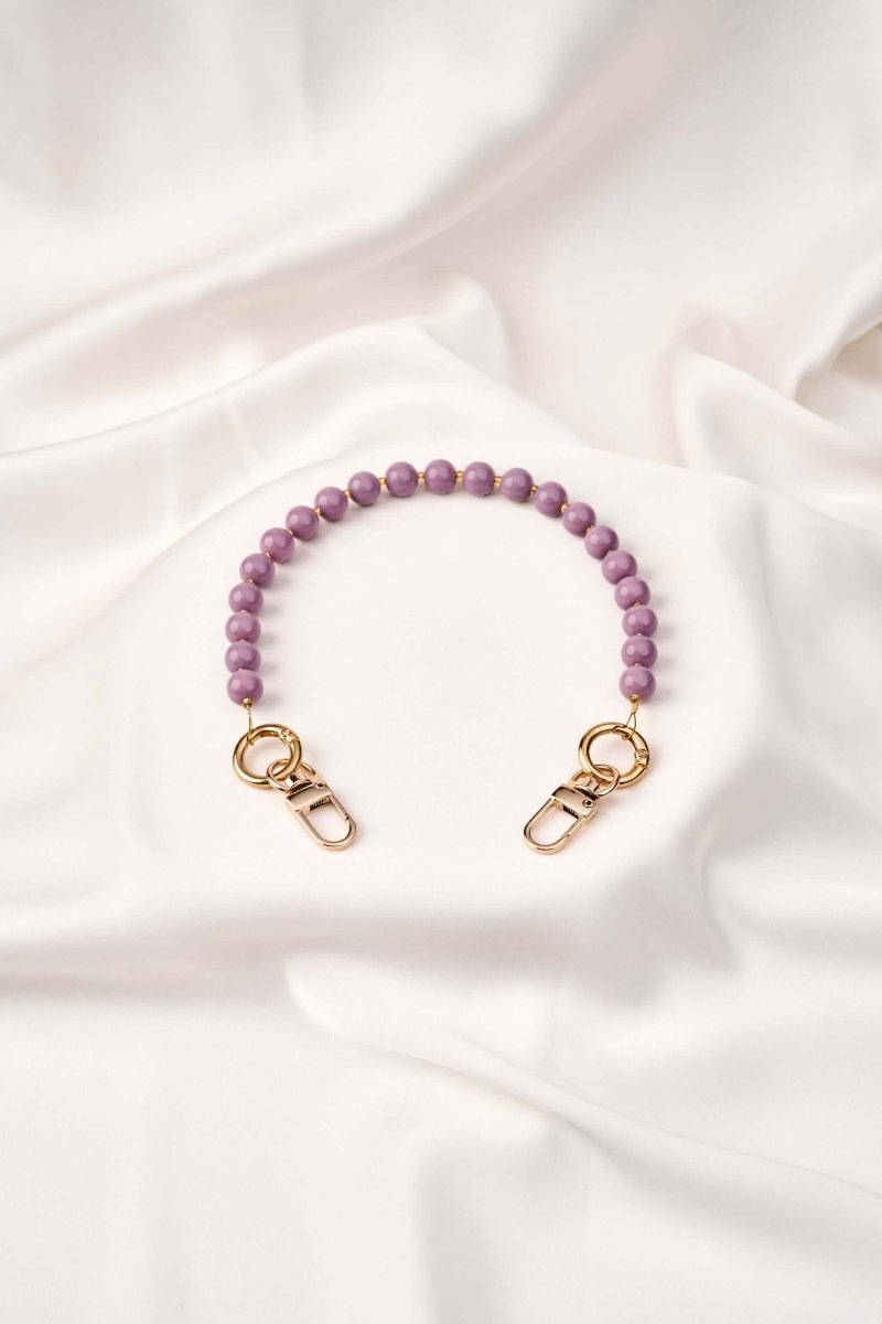strap celular Purple Flow, lujo artesanal colombiano con perlas y broches dorados, tejido a mano para mayor seguridad.
