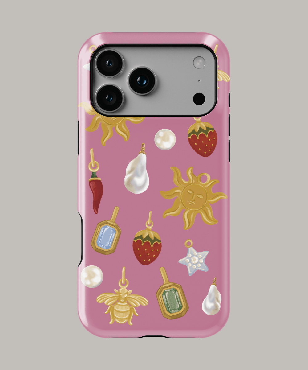 Funda resistente iPhone personalizada con diseño de frutas y charms coloridos sobre fondo rosa.