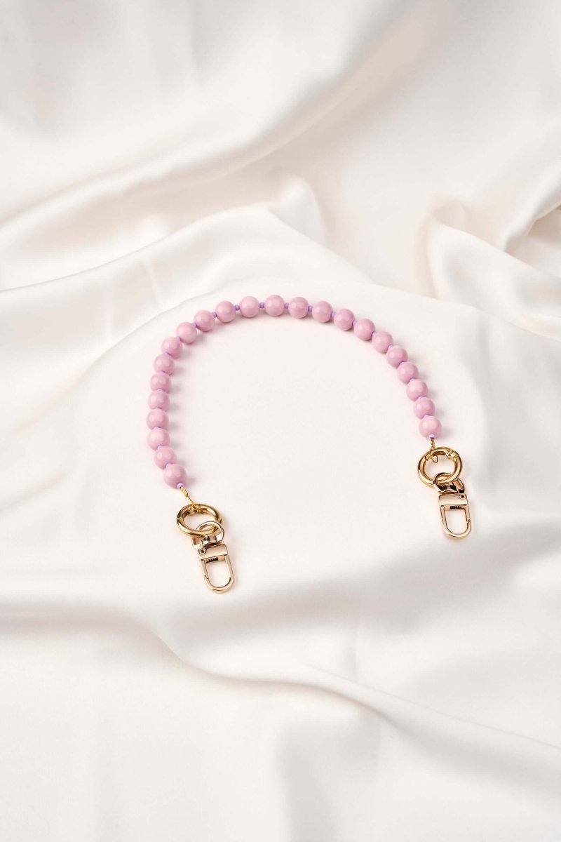 strap celular artesanal Soft Aura color rosa, elaborado a mano con perlas y broches de acero, fondo blanco.