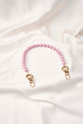 strap celular artesanal Soft Aura color rosa, elaborado a mano con perlas y broches de acero, fondo blanco.