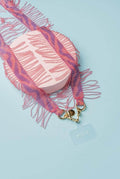 strap emilia flecos rosa artesanal con detalles en mostacilla y broches de acero dorado sobre fondo azul.